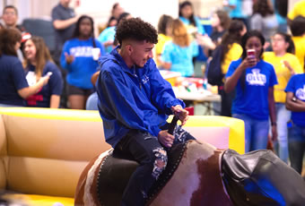 Male student riding mechanical bull 
